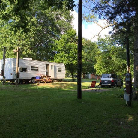 rv parked in grassy area with trees